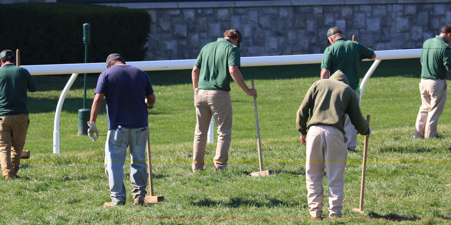 An action shot of Keenriders team members tamping down turf divots.